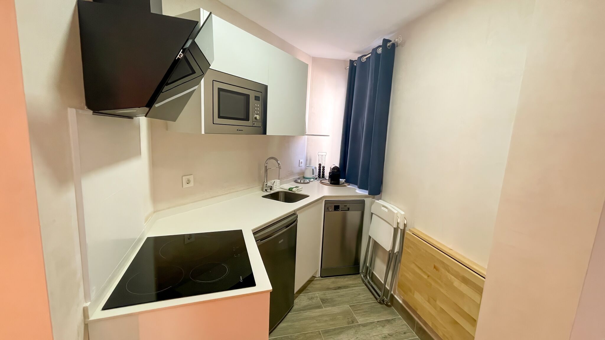 A compact kitchen with a microwave, sink, dishwasher, and a small stove.