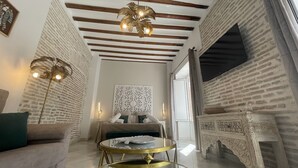 Une pièce avec un mur en briques, une cheminée, un lit avec des oreillers, une table ronde et un luminaire suspendu.