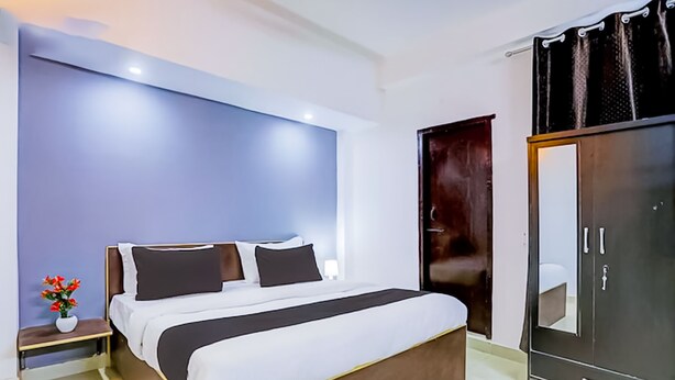 Habitació d'hotel moderna amb un llit gran, un armari i una tauleta de nit amb un ram de flors.