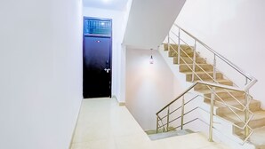 Un interior modern amb una escala, una porta i un lluminari.