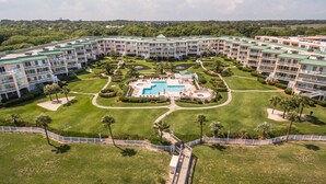 Un resort con varias edificaciones, una piscina central y céspedes bien cuidados.