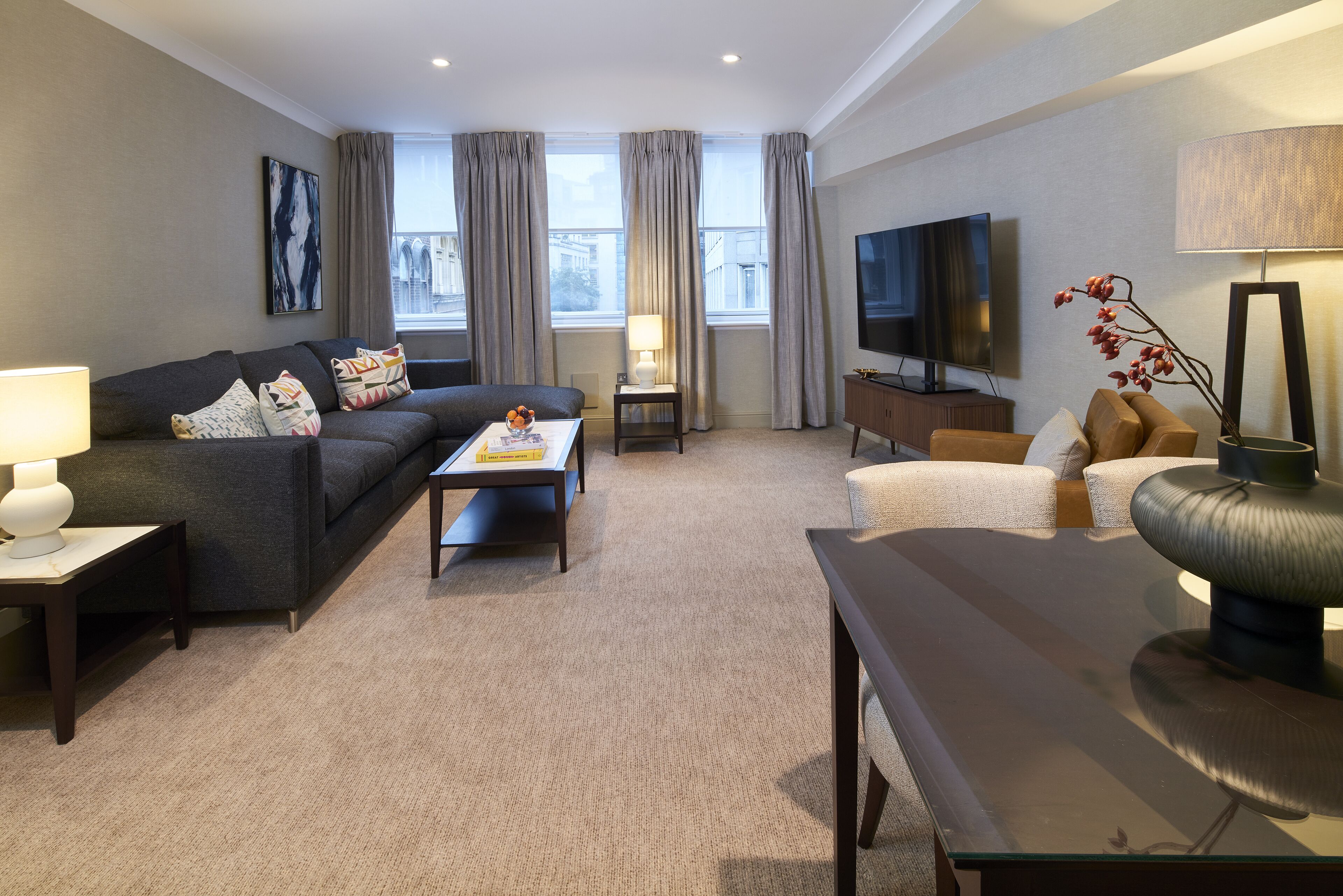 Ein modernes Wohnzimmer mit Sofa, Couchtisch, Fernseher und dekorativen Pflanzen.
