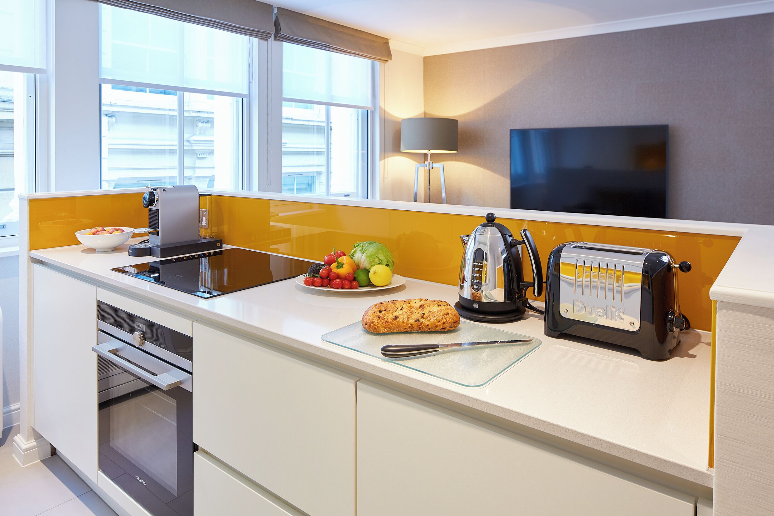 Eine moderne Küche mit eingebautem Ofen, einem Toaster und einer Obstschale auf der Arbeitsplatte.