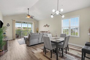 A dining area with a table and chairs, a ceiling fan, and a view through a sliding glass door.