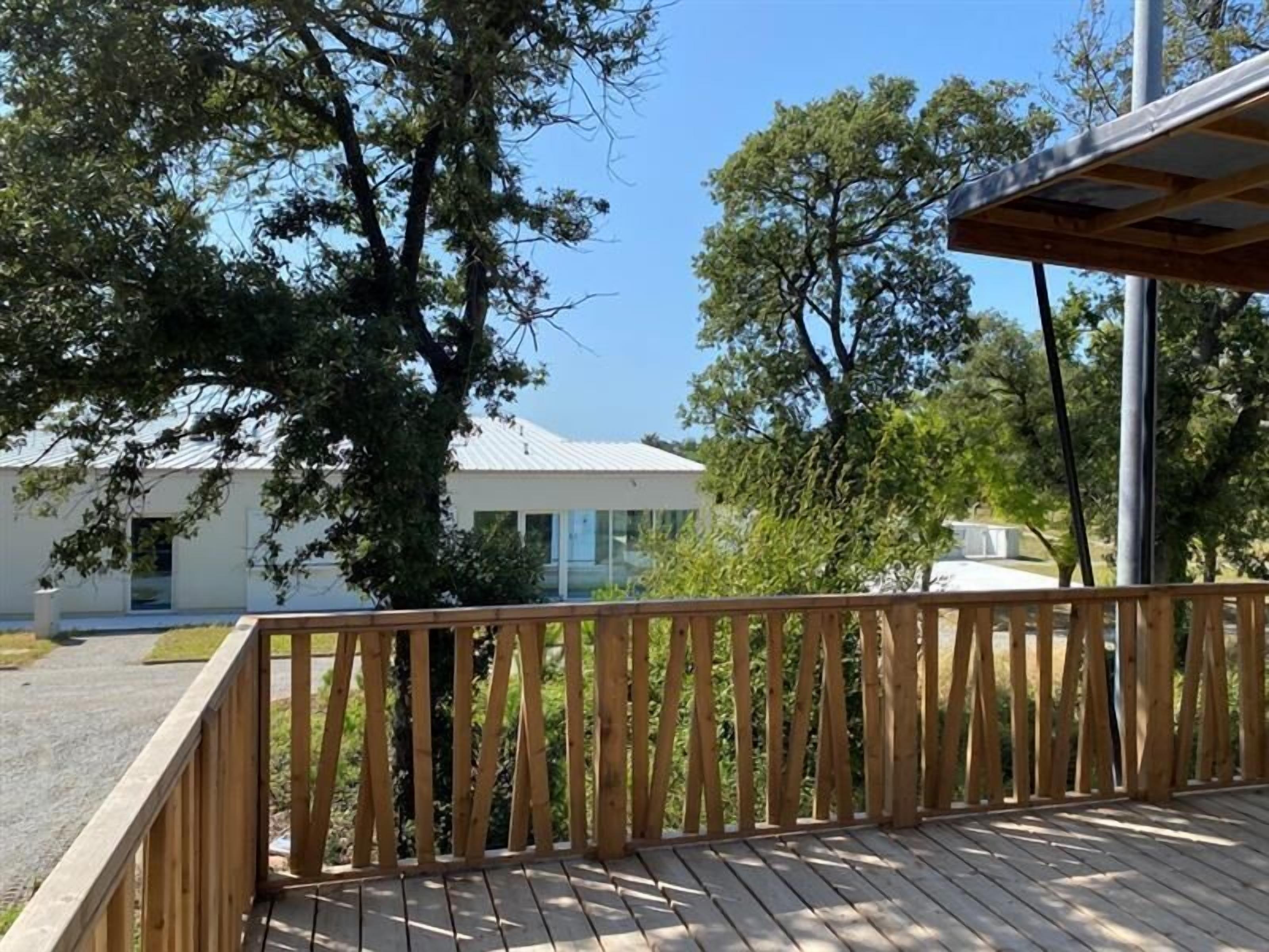 A wooden deck with a view of a modern building and surrounding trees.