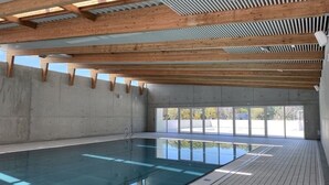 An indoor swimming pool with a tiled floor and wooden beams on the ceiling. - VVF Les Sableaux à Noirmoutier  (Noirmoutier-en-l'Ile)