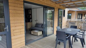A wooden cabin with a sliding glass door leading to a balcony with a table and chairs. - VVF Les Sableaux à Noirmoutier  (Noirmoutier-en-l'Ile)