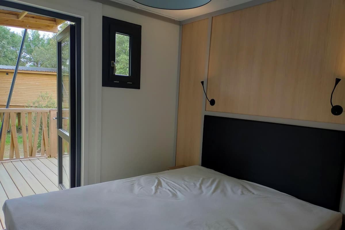 A bedroom with a bed, wooden wardrobe, and a small window.