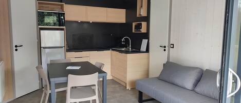 A compact living space with a kitchenette, a dining area with a table and chairs, and a sofa.