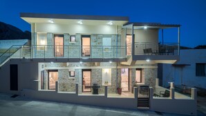 Une maison moderne à deux étages, dotée d’un balcon, de grandes fenêtres et d’une façade en pierre.
