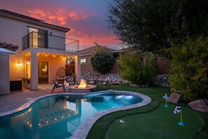 A backyard with a swimming pool, a fire pit, and a covered seating area with string lights. - Desert Arcade Oasis | Putt Putt, Pool & Fire Pit (Oro Valley)