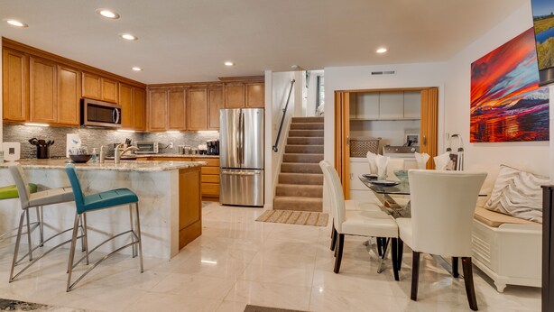 A modern kitchen with wooden cabinets, stainless steel appliances, and a central island with bar stools.