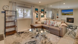 A modern living room with a sectional sofa, glass coffee table, and a large mirror reflecting the room.