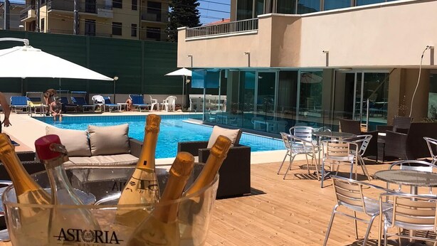 A poolside area with outdoor seating and a glass bowl of champagne bottles. - Hotel Apogeo  (Rimini)