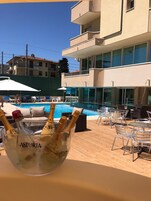 Zona junto a la piscina con mobiliario exterior y un bol de vidrio con botellas de champán.
