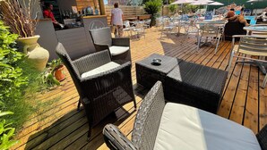 An outdoor patio area with wicker furniture, a bar, and umbrellas providing shade. - Hotel Apogeo  (Rimini)