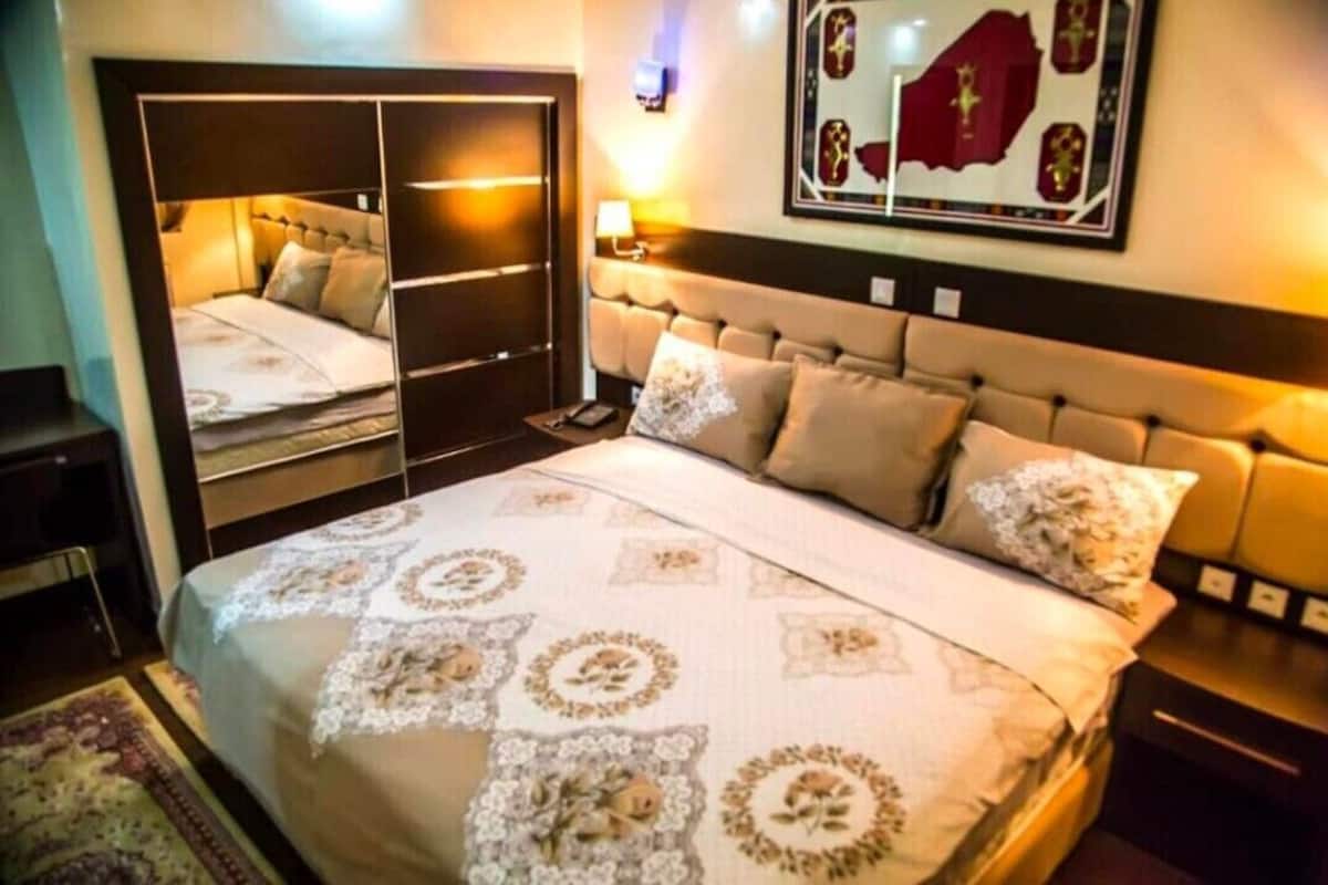 Un dormitorio con una cama grande, un armario, un espejo y una obra de arte colgada en la pared.