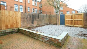 A brick patio with a raised garden bed, a wooden fence, and a blue gate. - 3 bed detached house in Telford (Telford and Wrekin)