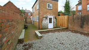A narrow alleyway with a small brick building, a wooden fence, and gravel ground. - 3 bed detached house in Telford (Telford and Wrekin)