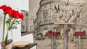 Ein Zimmer mit einem Wandgemälde einer Stadtansicht, einem Verbotsschild und zwei roten Stühlen.
