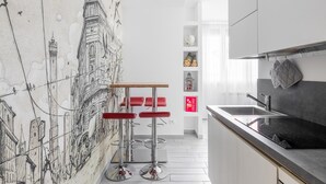 Eine moderne Küche mit Wandgemälde, Barhocker und Spüle.