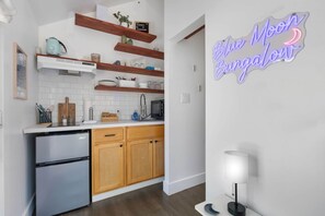 Eine moderne Küche mit Holzausstattung, einem eingebauten Backofen und einem Neon-Schild mit der Aufschrift 'Blue Moon Bungalow'.