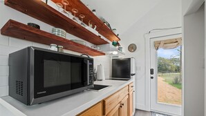 A kitchen with a large black microwave, wooden cabinets, and a white countertop. - North Star Nook | Tiny Home 6 Min from Old Tunnel (Kendall County)