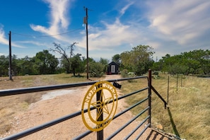 Un paysage rural avec une zone délimitée par une clôture, un petit bâtiment et un ciel dégagé.