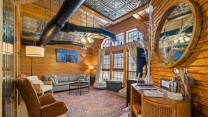 A cozy room with a wooden ceiling, a large mirror, a sofa, a coffee table, and a rug. - Twilight Ranch- 6 acre ranch w/2tiny homes & cabin (Kendall County)