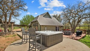 A hot tub with a pergola and chairs, a barbecue grill, and a covered patio area. - Twilight Ranch- 6 acre ranch w/2tiny homes & cabin (Kendall County)