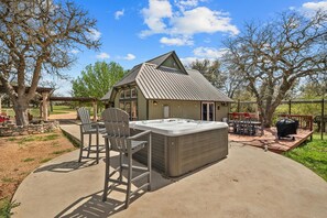 Relax in the hot tub surrounded by a patio and lush greenery.