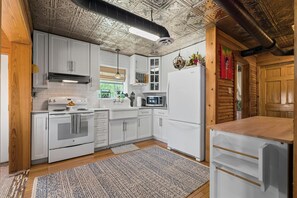 Kitchen features an oven, sink, and microwave, with a window above the sink.