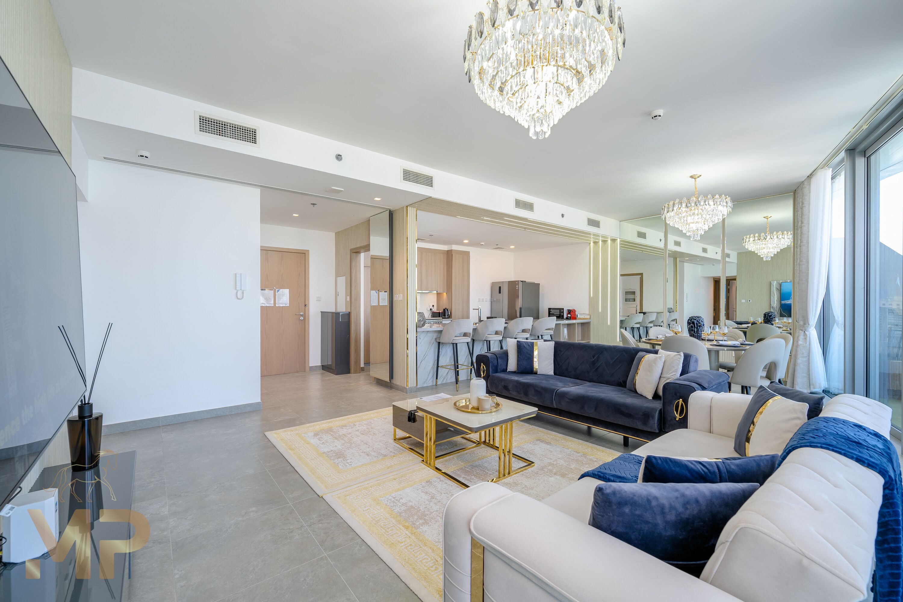 A spacious living area with a modern sofa set, a coffee table, and a chandelier.