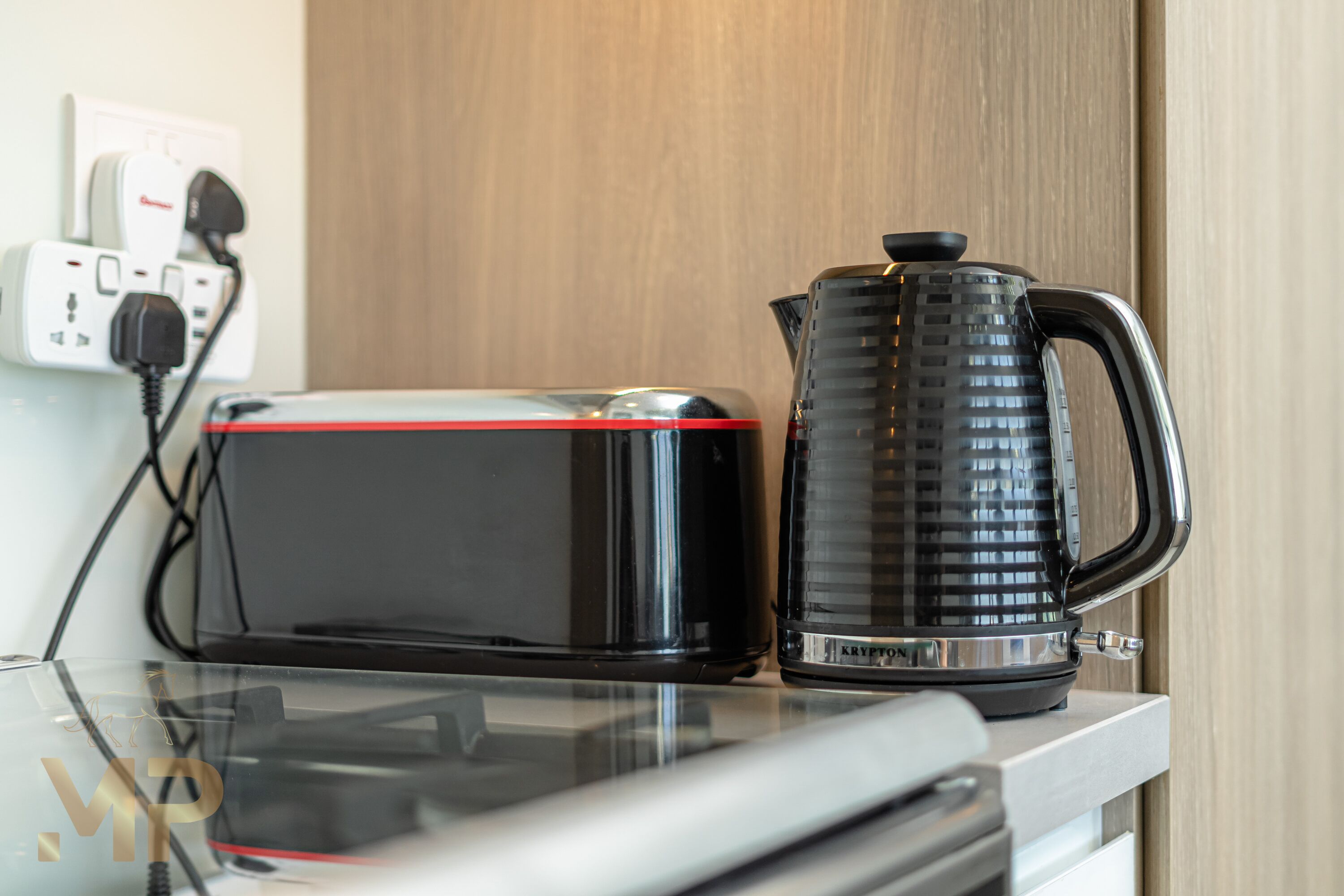 Ein Glastisch mit Toaster und Wasserkocher, beide schwarz.