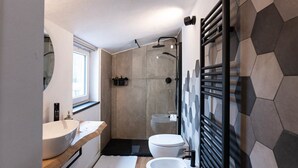 Une salle de bain moderne dotée d’un grand lavabo, de toilettes et d’un espace douche.
