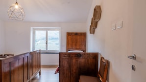 Une pièce comprenant un banc en bois, une armoire en bois, une tête de lit en bois et un luminaire suspendu.