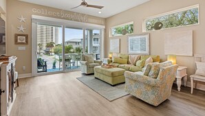 A spacious living room with a large window, a ceiling fan, and a fireplace. - Luxury Home 1 Block to Beach with Game Room (Jacksonville Beach)