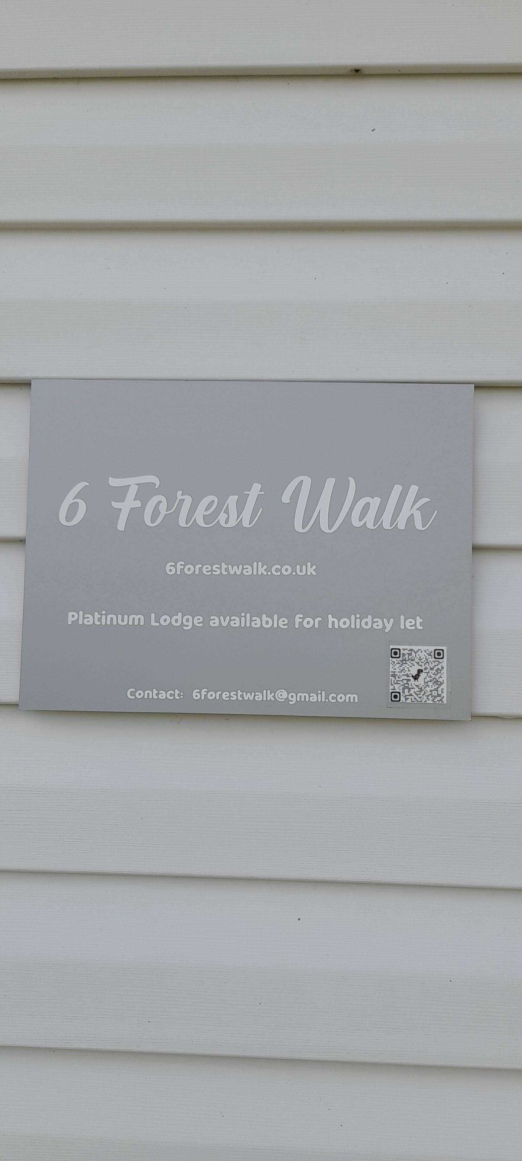Skilt for 6 Forest Walk, der angiver en Platinum Lodge til ferieleje.