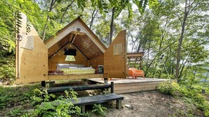 Una cabaña de madera con una cama, un banco y una pequeña mesa.