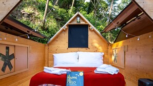 Una cabaña acogedora de madera con una cama, un libro de mapas, una maleta y un radio.