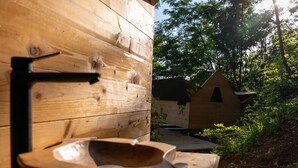 Una estructura de madera con diseño rústico, un banco de madera y una pequeña casa de madera al fondo.