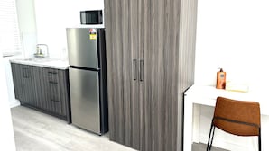 Una cuina moderna amb armaris grisos, un frigorífic d'acer inoxidable, un microones i un taulell blanc.
