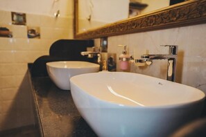 A bathroom with two white sinks, a mirror with an ornate frame, and a black countertop. - GoSolo Stays (Mumbai)