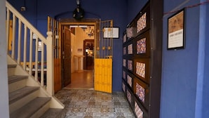 A hallway with a wooden staircase, a blue wall, and a patterned floor.