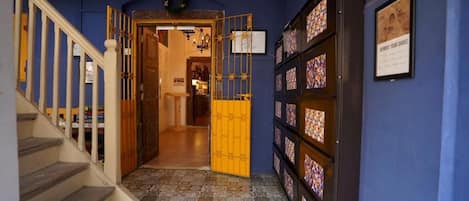 A hallway with a wooden staircase, a blue wall, and a patterned floor.