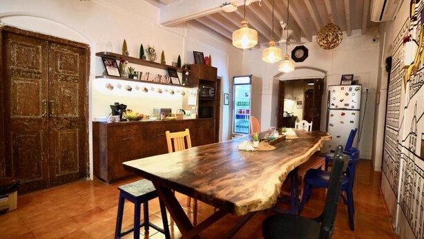 A kitchen with a wooden table, blue chairs, and hanging pendant lights.