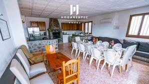Un grand espace de vie comprenant une table à manger, des chaises, un canapé et une cuisine à l’arrière-plan.