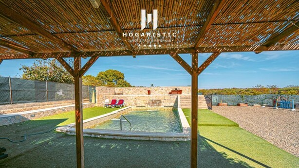 Un espace extérieur abrité comprenant une piscine, des chaises longues et une pergola.