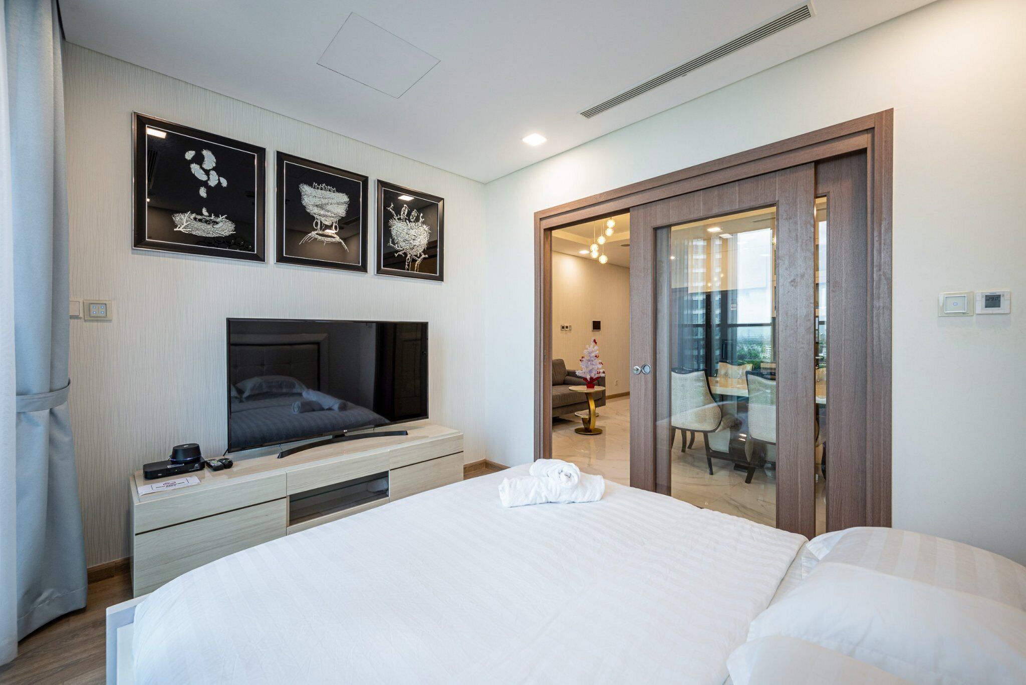 Une chambre d’hôtel moderne dotée d’un grand lit, d’un téléviseur à écran plat, d’un bureau avec une lampe et d’œuvres d’art accrochées au mur.