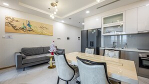 Una cocina moderna con comedor, que presenta suelo de mármol, sofá gris y mesa de comedor con sillas.